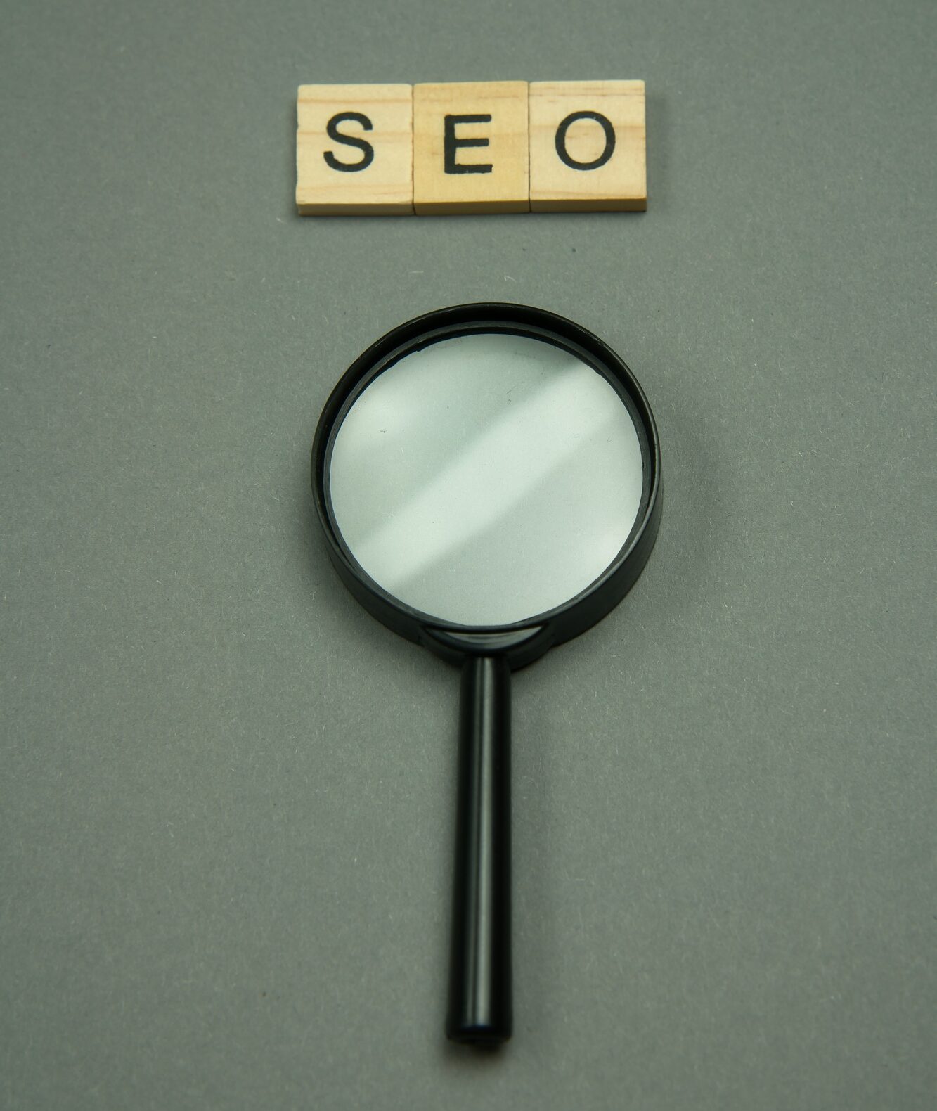 SEO written in wooden letters and magnifying glass.